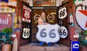 Harley Russell poses for a photo with some of his Route 66 signs in front of the Sandhills Curiosity Shop in Erick in this 2019 photo. [Photo by Jordan Green/The Blackwell Journal-Tribune]